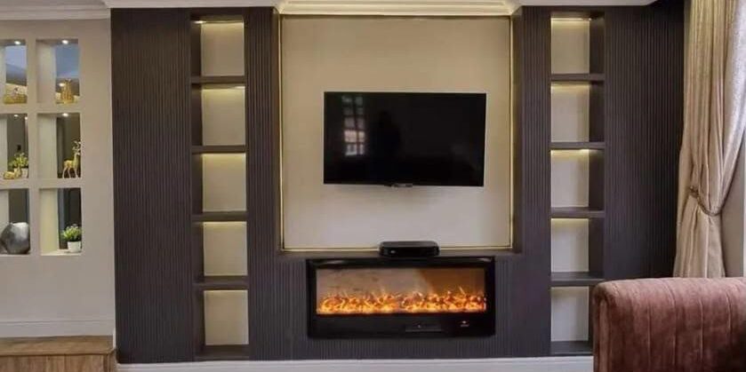 Living room media wall with electric fireplace, backlit shelving and wooden flooring by Shivin Interiors